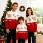 Family of three standing together in front of a Christmas tree wearing matching red reindeer knit sweaters.