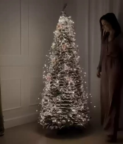 Pre-lit flocked Christmas tree with warm white lights indoors.