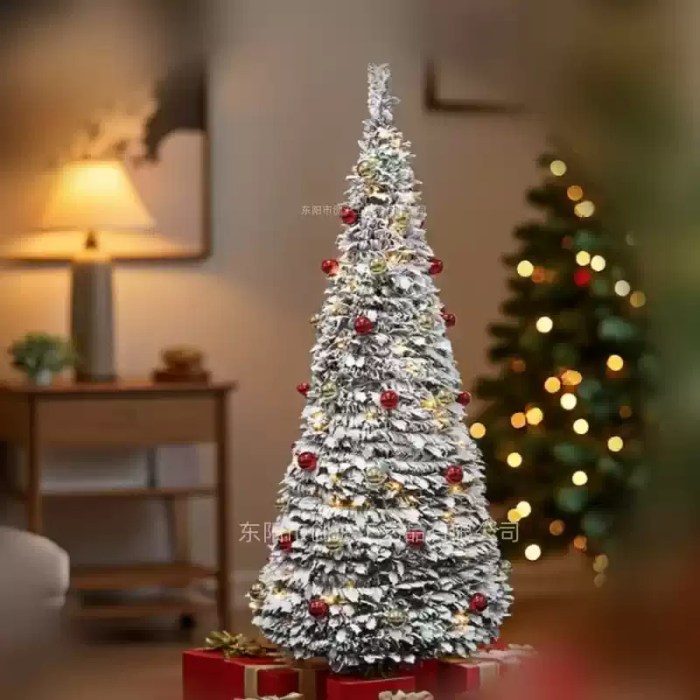 Snowy Christmas tree with warm lights and red festive baubles.