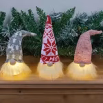 Christmas gnome ornaments arranged on a shelf with festive greenery